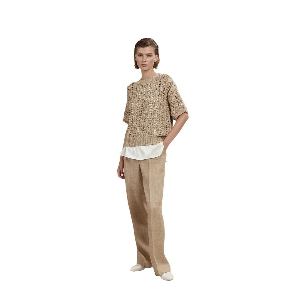 Vrouw in beige gebreide top met wijde beige pantalon en witte onderlaag